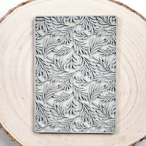 May include: A gray silicone stamp with a repeating pattern of stylized leaves. The stamp is rectangular and has the word "molko" printed in the top left corner.