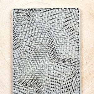 May include: A gray silicone pet feeding mat with a textured surface of small bumps in a wavy pattern. The mat has the word "moiko" printed in the top left corner.