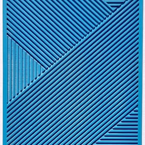 Puede incluir: Una estera de horno de silicona azul con un patrón geométrico de líneas diagonales. La estera tiene la palabra "moiko" impresa en la esquina superior izquierda.