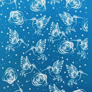 May include: A blue background with a repeating pattern of white hummingbirds and roses. The hummingbirds are flying and the roses are in bloom.