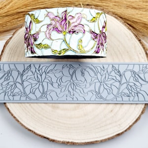 Pode incluir: Um molde de silicone cinza com um design floral. O molde tem a forma de um retângulo longo e apresenta um padrão repetitivo de flores e folhas. O molde é projetado para criar elementos decorativos para bolos, biscoitos ou outras sobremesas.