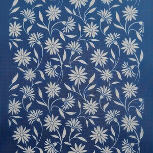 Pode incluir: Um estêncil azul com um padrão de margaridas brancas. O estêncil é feito de um material durável e é perfeito para criar belos designs em uma variedade de superfícies.