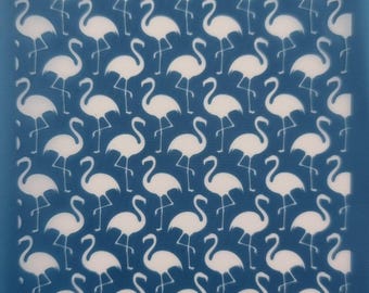 May include: A blue stencil with a repeating pattern of white flamingo silhouettes. The stencil is labeled "moiko 20.27" in the top left corner and "moiko" in the bottom right corner.