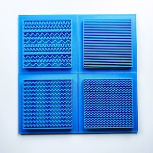 Puede incluir: Cuatro azulejos cuadrados azules con diferentes patrones en relieve. El azulejo superior izquierdo tiene un patrón ondulado, el azulejo superior derecho tiene un patrón de línea recta, el azulejo inferior izquierdo tiene un patrón ondulado y el azulejo inferior derecho tiene un patrón ondulado.