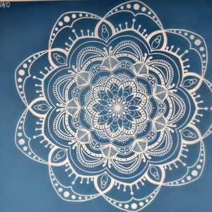May include: A white mandala design on a blue background. The mandala is intricate and detailed, with many layers of circles and patterns.