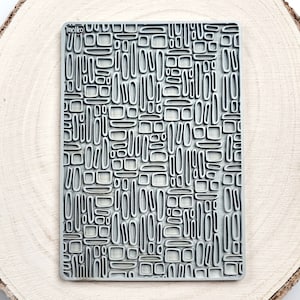 May include: A grey rubber stamp with a geometric pattern of various sized ovals and rectangles. The stamp is labelled "moiko" in the top left corner.