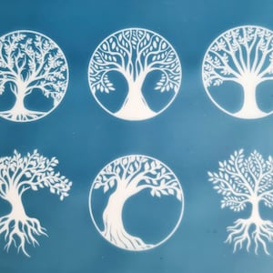 Op de afbeelding: Zes witte boom des levens sjablonen op een blauwe achtergrond. De sjablonen zijn rond met een boomontwerp erin. De bomen hebben takken en wortels.