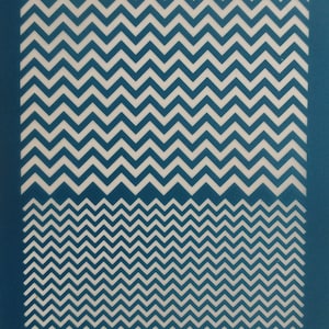 Puede incluir: Una plantilla de plástico azul con un patrón de chevron blanco. La plantilla tiene la palabra "moiko" impresa en blanco en la parte superior e inferior.