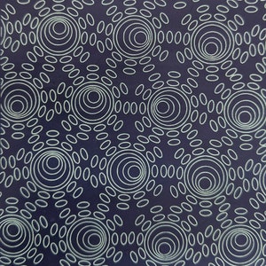 May include: A dark blue fabric with a white pattern of concentric circles and small ovals. The pattern is repeated throughout the fabric.