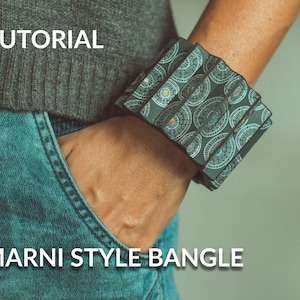 May include: A black and white patterned bangle bracelet with a geometric design. The bracelet is worn on a person's wrist. The text "MARNI STYLE BANGLE" is visible below the bracelet.