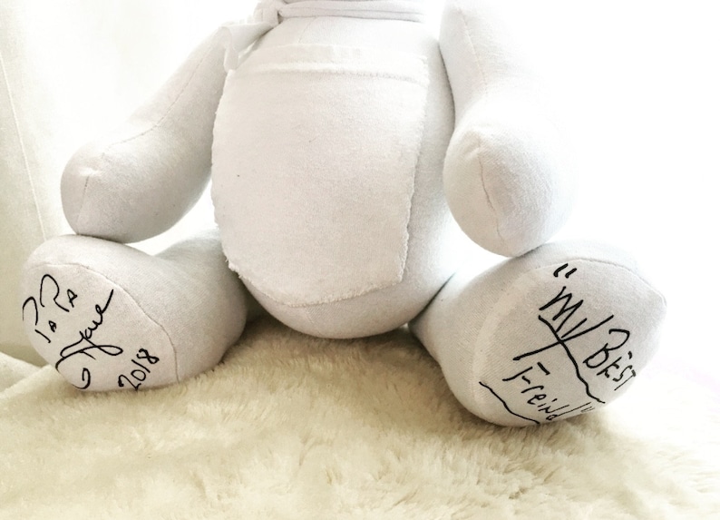 May include: A white fabric teddy bear with a rounded torso and limbs. The left foot features black handwritten text that reads "Papa" and "2018". The right foot features black handwritten text that reads "My Best Friend" with a line underneath.