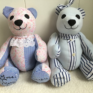 May include: Two handmade fabric teddy bears. The left bear features pink floral and blue striped fabric with a white lace collar. The right bear is light blue with blue striped accents and a button-down front. Both have black eyes and noses.