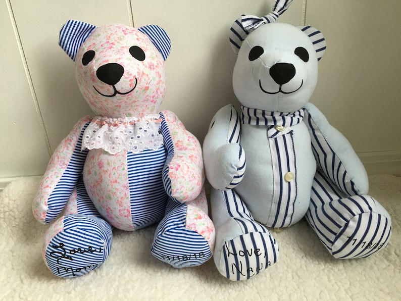 May include: Two handmade fabric teddy bears. The left bear features pink floral and blue striped fabric with a white lace collar. The right bear is light blue with blue striped accents and a button-down front. Both have black eyes and noses.