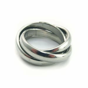 May include: A silver-colored ring with three interlocking bands. The bands are smooth and shiny, reflecting light. The ring is set against a white background.