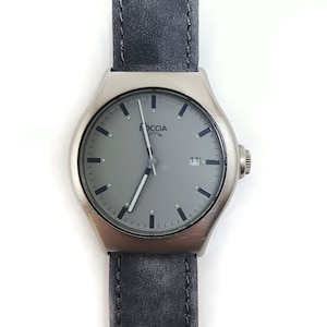 Puede incluir: Un reloj de pulsera plateado con una esfera gris y agujas negras. El reloj tiene una correa de cuero negra y la palabra "Boccia Titanium" está impresa en la esfera.