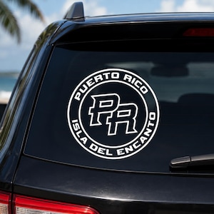 May include: A circular white vinyl decal applied to a car rear window. The design features the letters PR in the center, surrounded by a circular border containing the text PUERTO RICO and ISLA DEL ENCANTO in a bold, sans-serif white font.