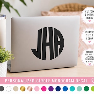 May include: A black circular monogram decal featuring the letters JHA applied to the center of a silver laptop lid. The decal has a bold, vertical striped font style. Below the laptop, a color palette shows various circular color swatches.