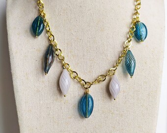 Gold crew neck necklace with hanging blue puffed glass pendants