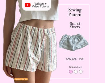 May include: Cream-colored shorts with vertical stripes in red, gray, and blue. The image also shows a smaller pair of blue and white striped shorts. Text on the image reads "Sewing Pattern Scandi Shorts" and "Written + Video Tutorial".