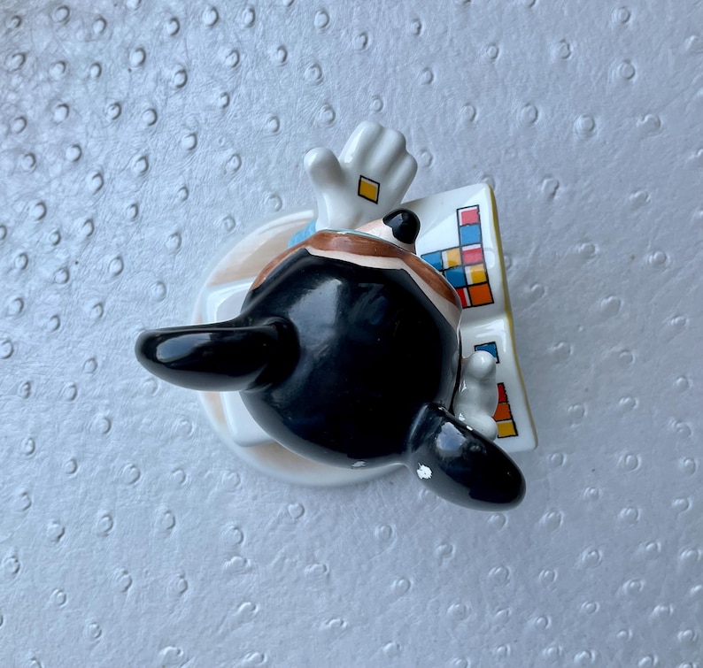 Puede incluir: Una figura de cer&aacute;mica de una figura de pelo negro con un traje, con un guante blanco y un dise&ntilde;o colorido. La figura tiene una base redonda con un dise&ntilde;o marr&oacute;n claro y azul.