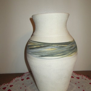 May include: White ceramic vase with a textured surface and a band of green, yellow, and gray brushstrokes around the middle.