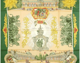 May include: A square silk scarf with a green border and a cream-colored center. The scarf features illustrations of buildings, people, and ornate designs in shades of green, gold, and red. The word "PARIS" is visible.