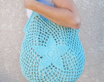 May include: A light blue crocheted tote bag with a large star design in the center. The bag is made of a lightweight, open-weave material.