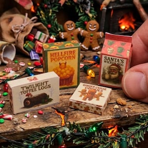 Può includere: Una collezione di quattro scatole di cibo in miniatura tra cui Hellfire Popcorn, Santa's Wicked Nog, Twilight Toffee Logs e Ginger Curse Cookies. Le piccole confezioni rettangolari presentano grafiche festive e del testo.