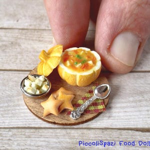 Può includere: Set di cibo in miniatura per casa delle bambole su un piatto di legno. Include una ciotola di zuppa in una zucca intagliata, una piccola ciotola di cubetti di pane, biscotti a forma di stella e un cucchiaino.