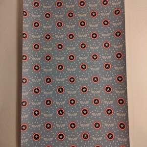 May include: A blue fabric with a repeating pattern of white stars and red, white, and blue Captain America shields.