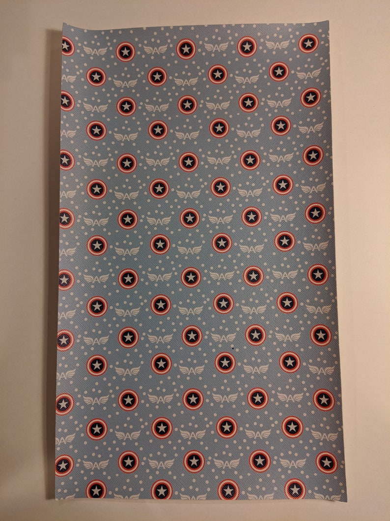 May include: A blue fabric with a repeating pattern of white stars and red, white, and blue Captain America shields.