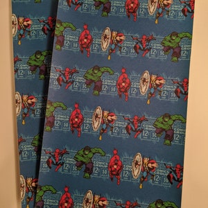 May include: Three sheets of blue fabric with a repeating pattern of Marvel Comics characters, including Spider-Man, Hulk, Captain America, and Daredevil. The fabric has a textured surface and the characters are in a retro comic book style. The text "Marvel Comics Group 12&cent; 50" is repeated throughout the pattern.