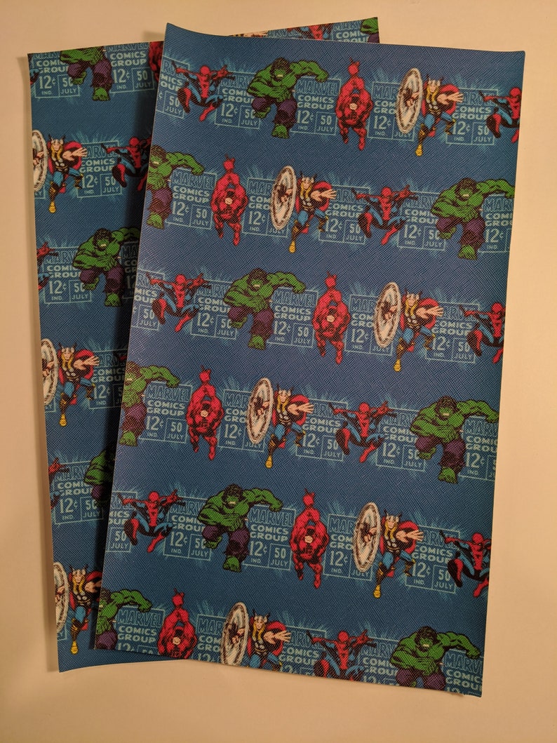 May include: Three sheets of blue fabric with a repeating pattern of Marvel Comics characters, including Spider-Man, Hulk, Captain America, and Daredevil. The fabric has a textured surface and the characters are in a retro comic book style. The text "Marvel Comics Group 12&cent; 50" is repeated throughout the pattern.