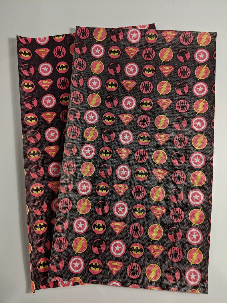 May include: Two sheets of black fabric with a repeating pattern of red circles containing superhero logos. The logos include Batman, Superman, Spiderman, The Flash, and Thor's hammer.