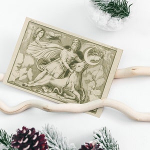 May include: A rectangular print featuring a monochromatic illustration of a figure riding a bull, accompanied by a crescent moon and a bird. The artwork includes the text 'Planche 2' in the top left corner and 'Pl. XIV' in the top right corner.