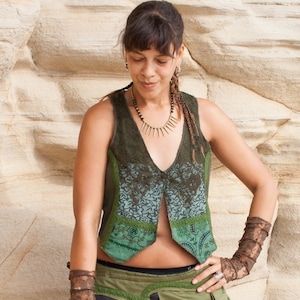 Könnte beinhalten: Eine Frau trägt eine grün-braune Weste mit einer Spitzenüberlagerung, einen grün-braunen Rock und braune Spitzenhandgelenksmanschetten. Sie trägt eine goldene Halskette mit einem spitzen Design.