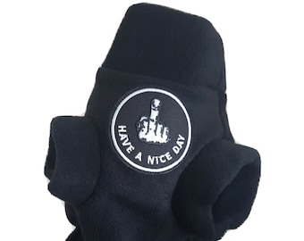 May include: Black fleece hat with ear flaps and a circular patch. The patch features a white hand giving the middle finger, with the words "HAVE A NICE DAY" in a circle around it. The hat is made of a soft, fuzzy material.