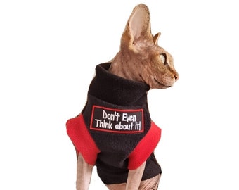 Puede incluir: Un gato sin pelo con un suéter de lana negro con mangas rojas. El suéter tiene el texto "Don't Even Think about It!" bordado en la parte delantera.