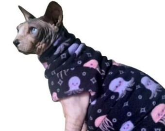 May include: A hairless cat wearing a black fleece sweater with a pink and purple octopus print.