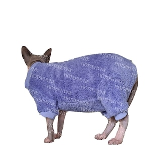 May include: A purple fuzzy cat onesie with long sleeves and legs. The onesie is made of a soft, plush material and has a zipper closure in the back.