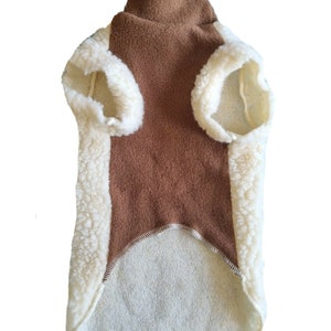 May include: A brown fleece dog sweater with a white sherpa trim. The sweater has a turtleneck and a long body.