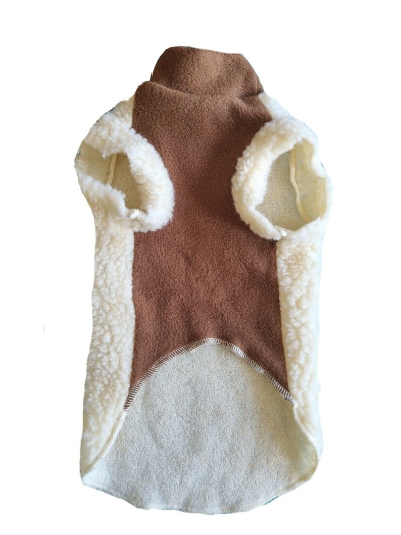 May include: A brown fleece dog sweater with a white sherpa trim. The sweater has a turtleneck and a long body.