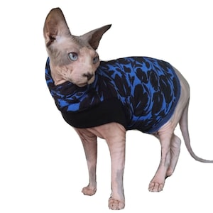 May include: A hairless cat wearing a blue and black patterned sweater. The sweater has a high neck and a long sleeve design.
