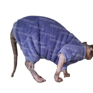 May include: A purple fuzzy cat sweater for a small dog or cat. The sweater has long sleeves and a turtleneck.
