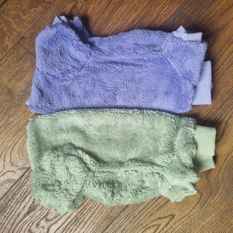 May include: Two soft, fuzzy sweaters, one in a light lavender color and the other in a pale green color. Both sweaters have a ribbed knit collar and cuffs.