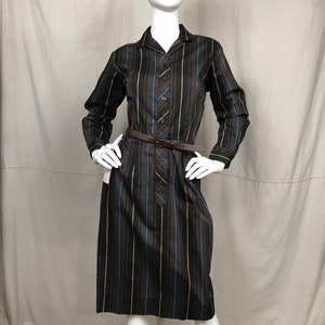 May include: A brown, black, and blue striped dress with a collared neckline and long sleeves. The dress has a brown belt and button closure.