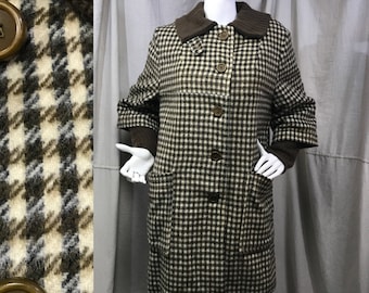 May include: A vintage houndstooth coat in brown, black, and cream. The coat features a brown knit collar and cuffs, large brown buttons, and two front pockets. The coat is displayed on a mannequin.