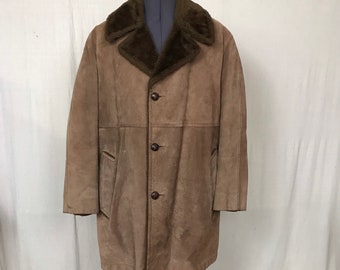 Könnte beinhalten: Ein Vintage-Mantel aus braunem Wildleder mit einem dunkelbraunen Shearling-Kragen. Der Mantel hat eine Knopfleiste, zwei Vordertaschen und ein knielanges Design. Der Mantel wird auf einer Schaufensterpuppe präsentiert.