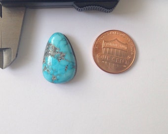 May include: A turquoise cabochon gemstone in a teardrop shape, measuring approximately the size of a US penny. The stone has a blue-green color with brown and gray matrix inclusions.