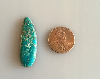 May include: A turquoise cabochon gemstone with brown and white markings. The gemstone is teardrop shaped and is about the size of a US penny.